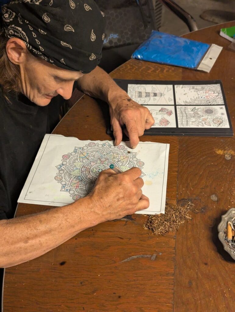 A participant adds color to a detailed mandala-style drawing