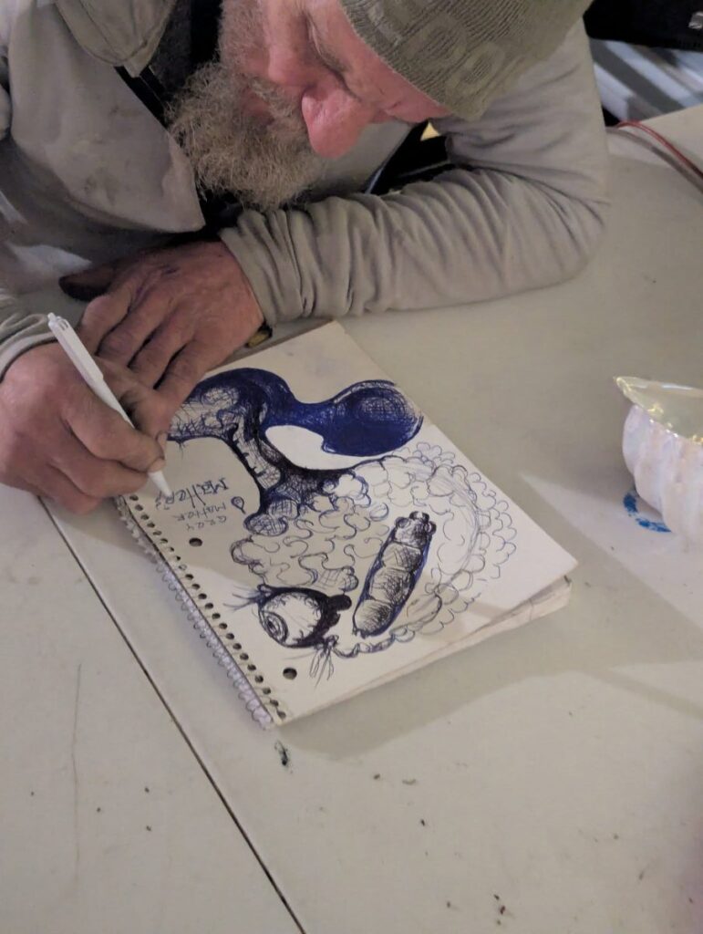 A participant sketches a character study in a spiral notebook