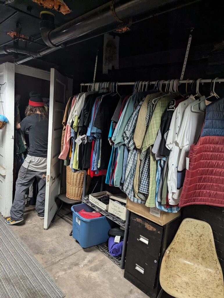 A rack of donated clothing and coats, with storage bins below