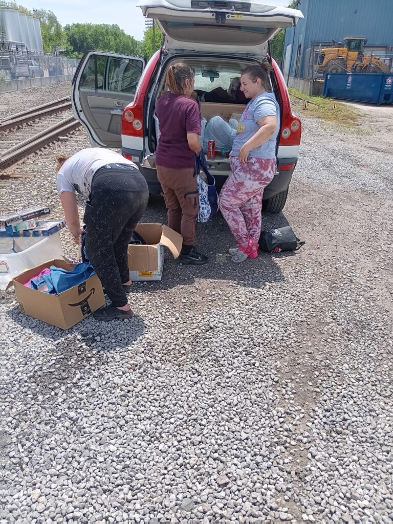 Second Chance Village volunteers deliver supplies from the back of a car during mobile outreach