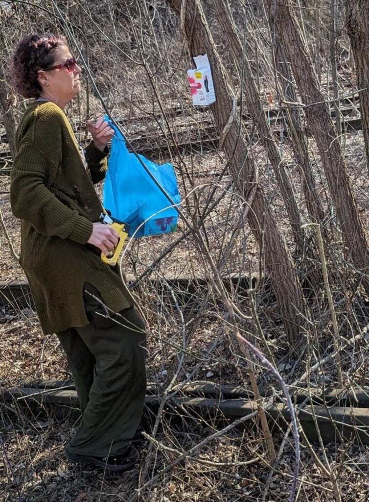 A Second Chance Village volunteer carries a bag of supplies through the woods to deliver to someone